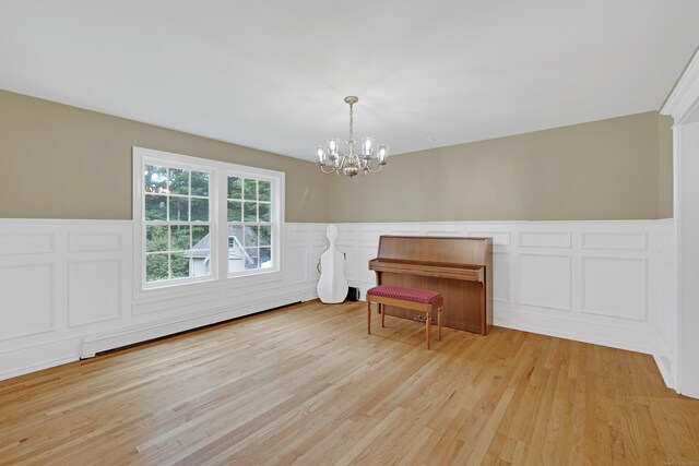 19 Maplecrest Dr, Danbury, CT 06811 - unfurnished room with a baseboard radiator, a chandelier, a decorative wall, light wood finished floors, and a wainscoted wall