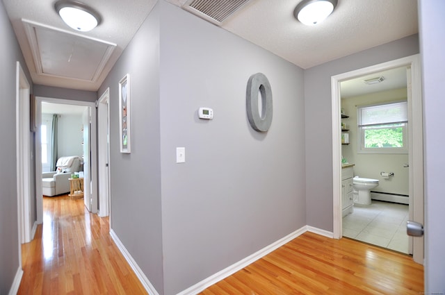 59 Settlers Knl, Newington, CT 06111 - hallway with baseboard heating, attic access, light wood-style floors, baseboards, and a textured ceiling