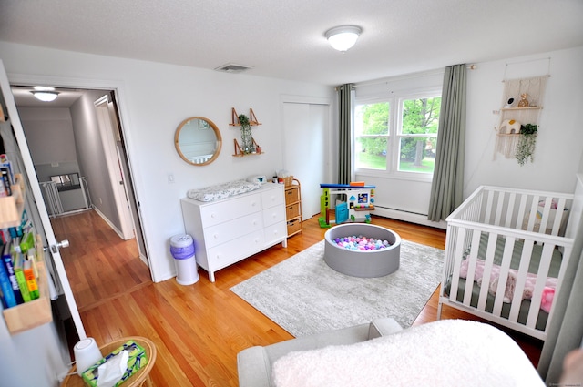 59 Settlers Knl, Newington, CT 06111 - bedroom featuring baseboard heating, light wood-style floors, and a nursery area