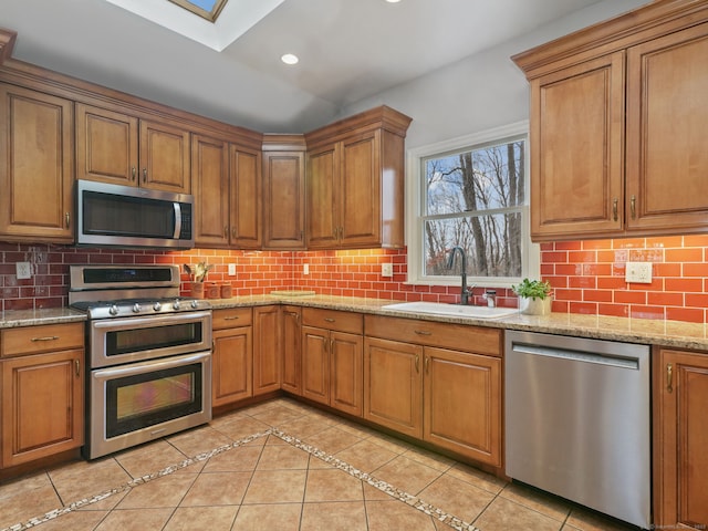 235 Lonetown Rd, Redding, CT 06896 - kitchen featuring appliances with stainless steel finishes, a sink, brown cabinets, a skylight, and recessed lighting