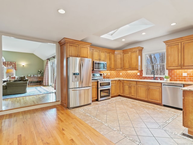 235 Lonetown Rd, Redding, CT 06896 - kitchen featuring appliances with stainless steel finishes, vaulted ceiling, a skylight, tasteful backsplash, and a sink