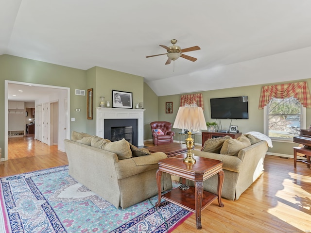 235 Lonetown Rd, Redding, CT 06896 - living room with vaulted ceiling, a ceiling fan, light wood-style floors, a glass covered fireplace, and baseboards