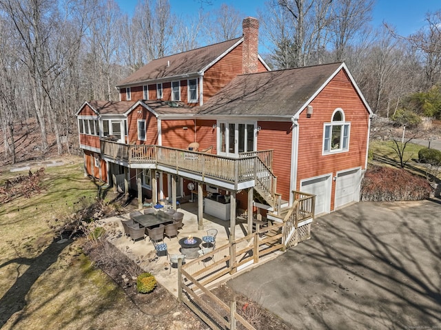 235 Lonetown Rd, Redding, CT 06896 - back of property with asphalt driveway, a wooden deck, a chimney, stairway, and an attached garage