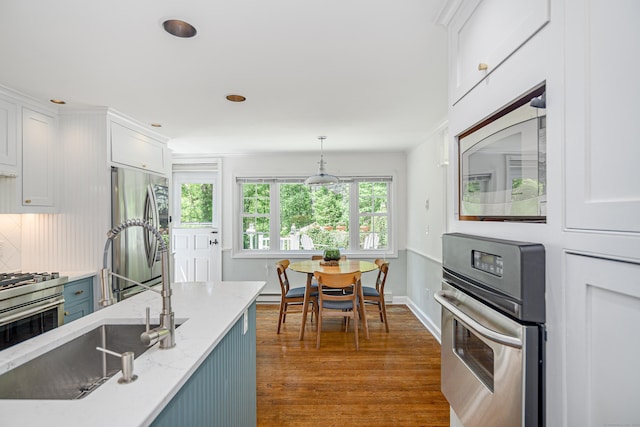 77 Crest Rd, Middlebury, CT 06762 - kitchen with stainless steel appliances, wood finished floors, white cabinetry, light stone counters, and hanging light fixtures