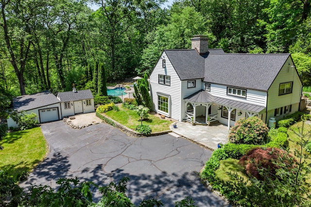 77 Crest Rd, Middlebury, CT 06762 - view of front of house with a standing seam roof, asphalt driveway, roof with shingles, metal roof, and a chimney