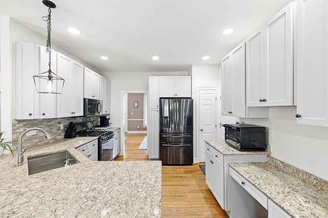 55 Perry Ln, Stratford, CT 06614 - kitchen with appliances with stainless steel finishes, a sink, light wood-style flooring, light stone countertops, and white cabinetry