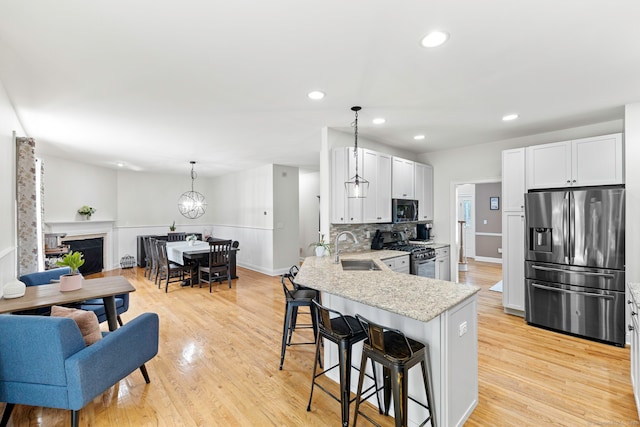 55 Perry Ln, Stratford, CT 06614 - kitchen with appliances with stainless steel finishes, a sink, a breakfast bar area, a peninsula, and light stone countertops