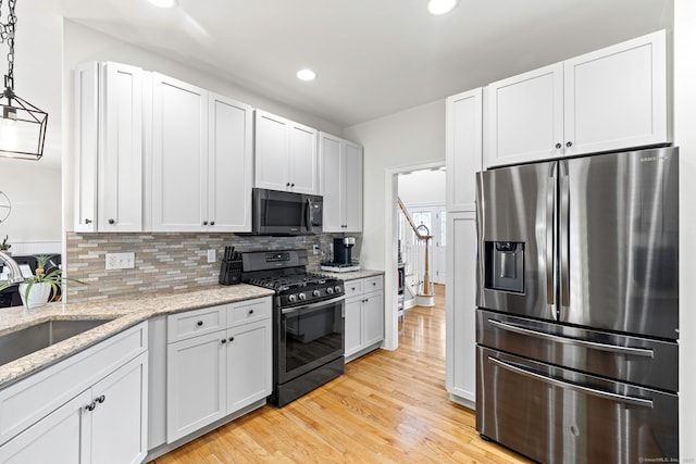 55 Perry Ln, Stratford, CT 06614 - kitchen featuring stainless steel fridge, black range with gas stovetop, recessed lighting, light wood finished floors, and backsplash