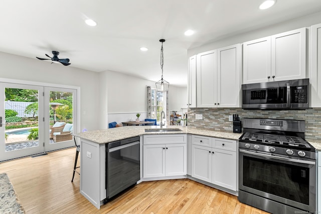 55 Perry Ln, Stratford, CT 06614 - kitchen featuring stainless steel appliances, a sink, a peninsula, backsplash, and light wood-style floors