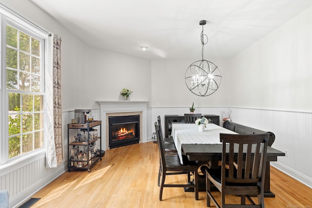 55 Perry Ln, Stratford, CT 06614 - dining room featuring light wood-style floors, a wainscoted wall, a glass covered fireplace, and a chandelier