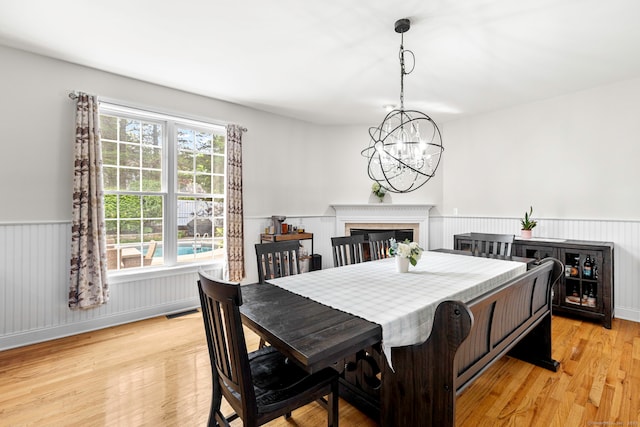 55 Perry Ln, Stratford, CT 06614 - dining room with a wainscoted wall, a chandelier, light wood-type flooring, and a glass covered fireplace