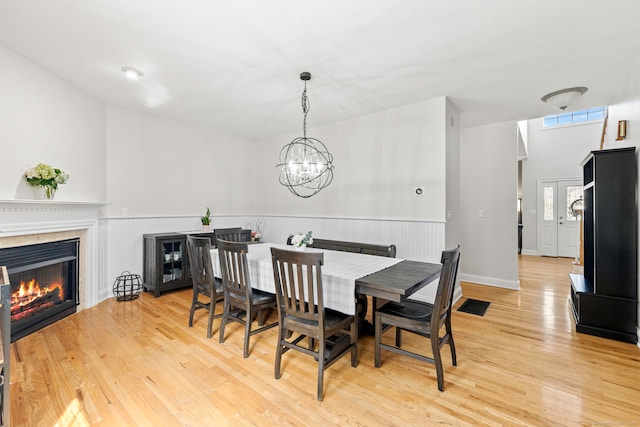 55 Perry Ln, Stratford, CT 06614 - dining space with light wood-style flooring, a chandelier, and a tiled fireplace