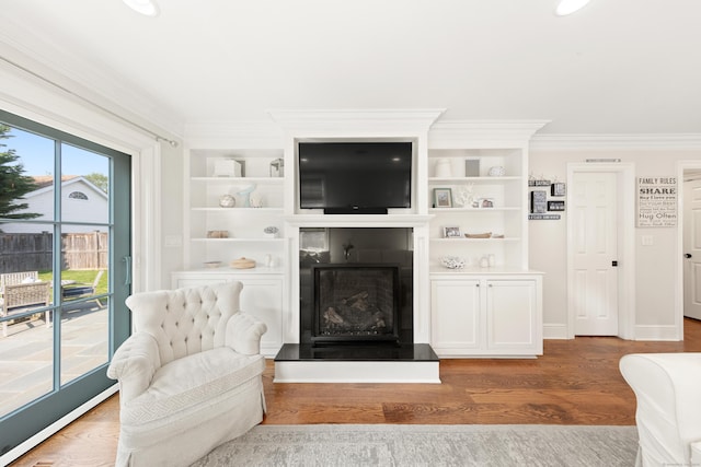 334 W Ave, Darien, CT 06820 - living area with a fireplace with raised hearth, ornamental molding, wood finished floors, built in shelves, and baseboards