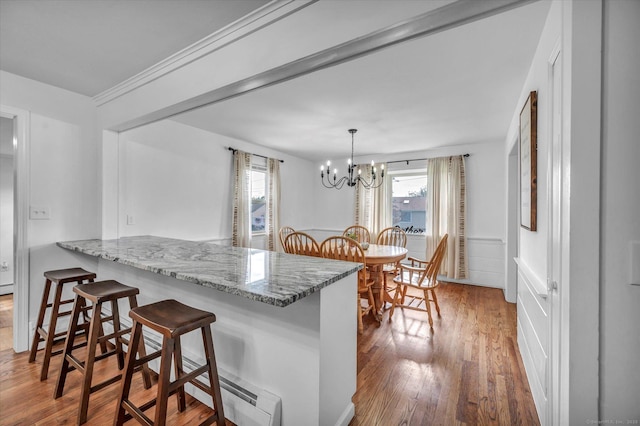 75 Carll Rd, Middletown, CT 06457 - kitchen featuring a chandelier, wood finished floors, a kitchen breakfast bar, a peninsula, and light stone countertops