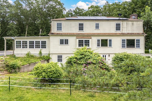 29 Daniels Rd, East Haddam, CT 06423 - rear view of property featuring roof mounted solar panels, a chimney, and view of wooded area