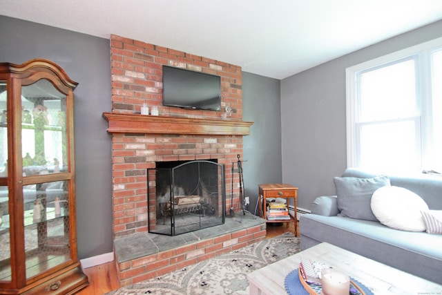 1 Deerfield Rd, Enfield, CT 06010 - living area with wood finished floors, a baseboard heating unit, and a brick fireplace