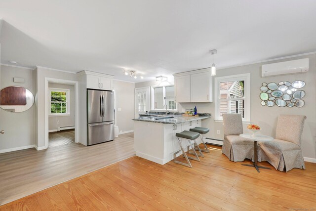 60 Indian Spring Rd, Woodstock, CT 06281 - kitchen with freestanding refrigerator, a wall unit AC, a peninsula, a baseboard radiator, and light wood finished floors