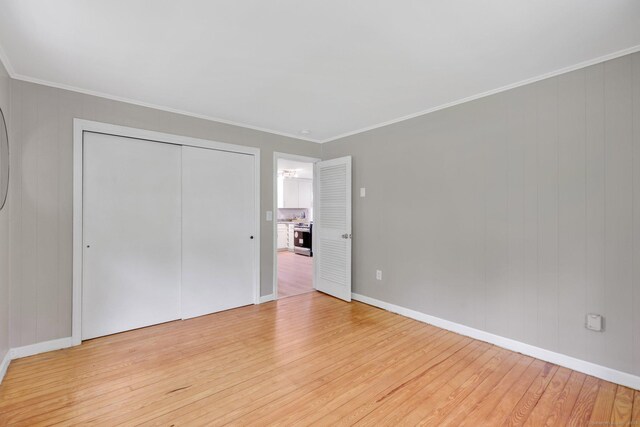 60 Indian Spring Rd, Woodstock, CT 06281 - unfurnished bedroom with light wood finished floors, crown molding, baseboards, a closet, and wood walls