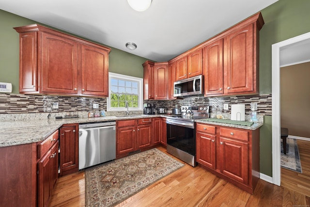 280 Ridgefield Ave, Waterbury, CT 06705 - kitchen featuring stainless steel appliances, light wood-type flooring, light stone counters, decorative backsplash, and a sink
