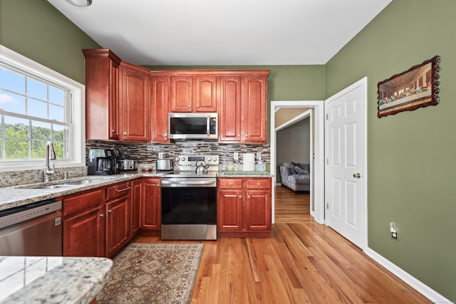 280 Ridgefield Ave, Waterbury, CT 06705 - kitchen featuring stainless steel appliances, a sink, backsplash, light stone counters, and light wood-style flooring