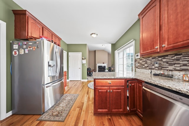 280 Ridgefield Ave, Waterbury, CT 06705 - kitchen featuring appliances with stainless steel finishes, a peninsula, lofted ceiling, tasteful backsplash, and a fireplace