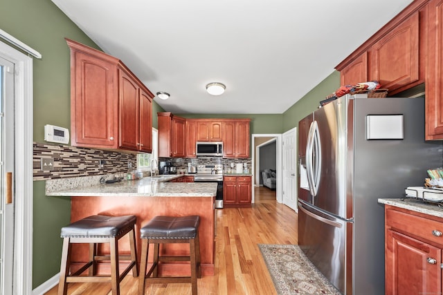280 Ridgefield Ave, Waterbury, CT 06705 - kitchen featuring stainless steel appliances, a sink, backsplash, light wood-type flooring, and a peninsula