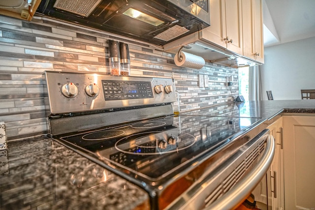 49 Hintz Dr, Wallingford, CT 06492 - kitchen view of stainless steel range with electric cooktop, tasteful backsplash, cream cabinetry, and dark stone counters