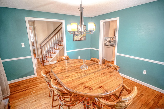 49 Hintz Dr, Wallingford, CT 06492 - dining room with a chandelier, stairway, light wood finished floors, baseboards, and a textured ceiling