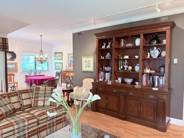 12 Heritage Crst Unit E, Southbury, CT 06488 - living room with track lighting, light wood-style floors, a chandelier, and crown molding