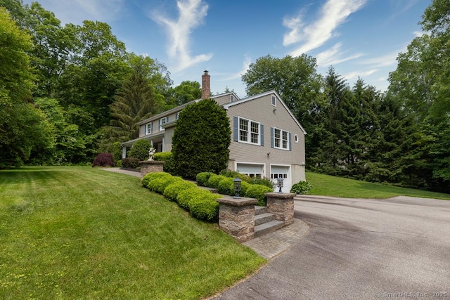 102 Pritchett Dr, Westbrook, CT 06498 - view of front facade with an attached garage, asphalt driveway, a chimney, and a front lawn