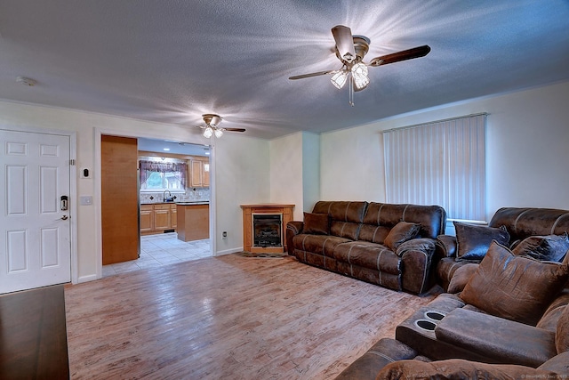 673 May St, Naugatuck, CT 06770 - living room with a ceiling fan, light wood-style flooring, a textured ceiling, and a fireplace