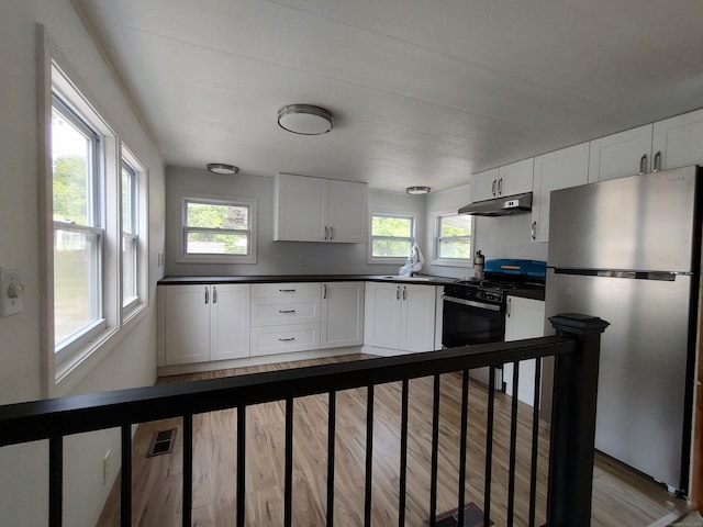 29 Hemlock Dr, Shelton, CT 06484 - kitchen with freestanding refrigerator, black range with gas cooktop, under cabinet range hood, dark countertops, and healthy amount of natural light