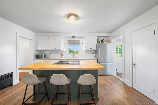 17 Wild Rose Pl, Waterford, CT 06385 - kitchen featuring stainless steel appliances, radiator heating unit, white cabinetry, and a kitchen breakfast bar