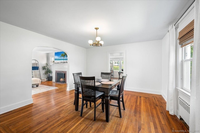 17 Wild Rose Pl, Waterford, CT 06385 - dining room with radiator heating unit, a brick fireplace, wood finished floors, baseboards, and a chandelier