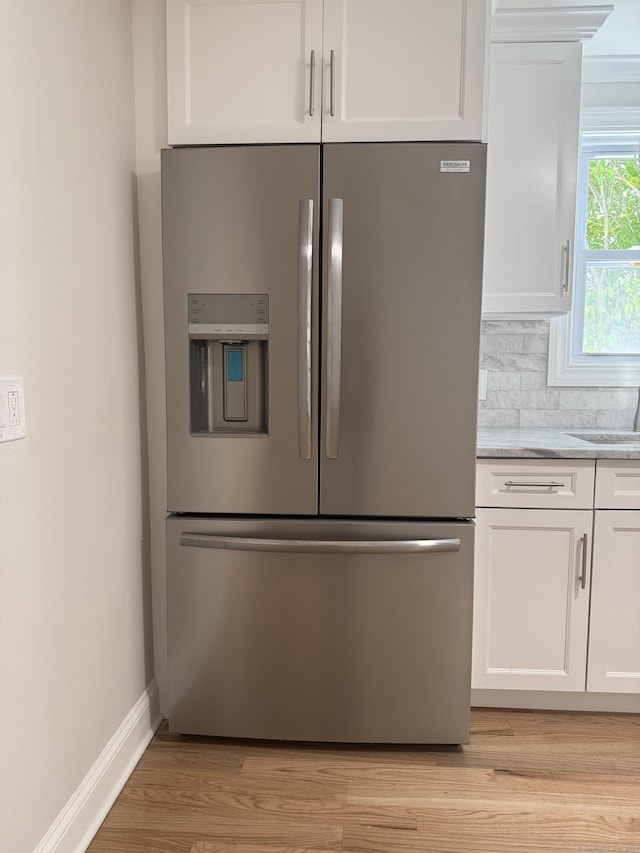 42 Waldo St, East Haven, CT 06512 - kitchen view of stainless steel fridge with ice dispenser, white cabinets, light wood-style flooring, and light stone countertops