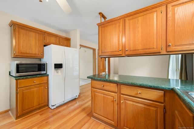 42 Cindy Ln, Groton, CT 06355 - kitchen featuring white refrigerator with ice dispenser, stainless steel microwave, light wood-style flooring, brown cabinetry, and dark countertops