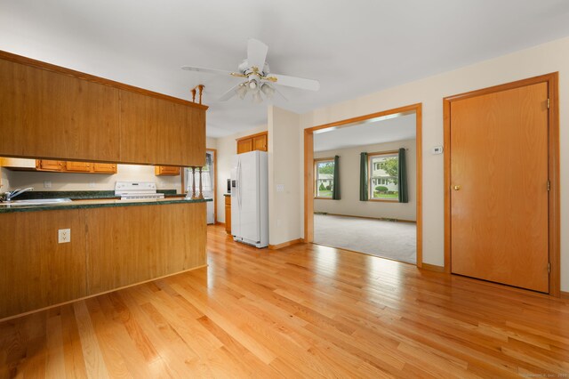 42 Cindy Ln, Groton, CT 06355 - kitchen with white appliances, dark countertops, light wood-type flooring, a peninsula, and a ceiling fan