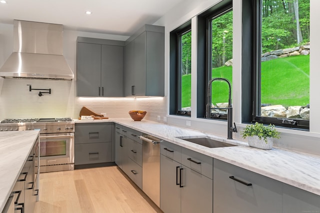 22 Limekiln Rd, Redding, CT 06896 - kitchen with gray cabinetry, wall chimney exhaust hood, stainless steel appliances, a sink, and light wood-style floors