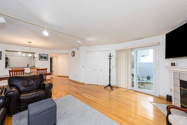 2 Mansfield Grove Rd Apt 160, East Haven, CT 06512 - living room with light wood-style flooring, a tiled fireplace, rail lighting, baseboards, and a textured ceiling