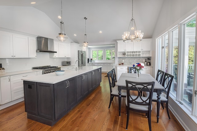 156 Main St, Ridgefield, CT 06877 - kitchen with wall chimney range hood, vaulted ceiling, high quality fridge, white cabinetry, and light countertops