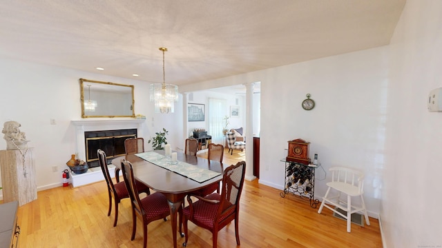 77 Bassett Rd, North Haven, CT 06473 - dining room featuring light wood finished floors, a glass covered fireplace, ornate columns, and baseboards