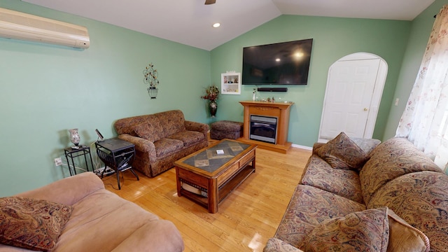 77 Bassett Rd, North Haven, CT 06473 - living area featuring a wall mounted AC, wood finished floors, vaulted ceiling, ceiling fan, and a glass covered fireplace