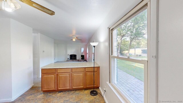 77 Bassett Rd, North Haven, CT 06473 - kitchen with light countertops, a ceiling fan, baseboards, brown cabinetry, and open floor plan