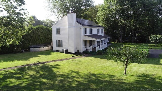 77 Bassett Rd, North Haven, CT 06473 - view of front of home with covered porch, a chimney, a covered pool, a front lawn, and roof with shingles