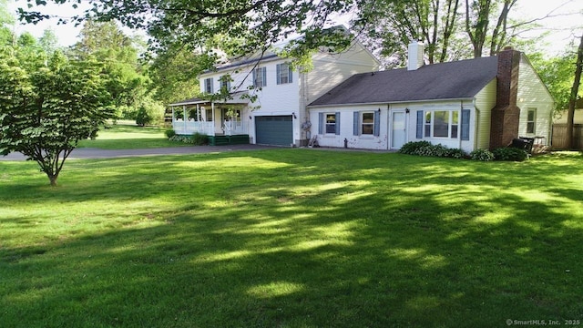 77 Bassett Rd, North Haven, CT 06473 - view of front of house with a garage, driveway, a chimney, and a front lawn
