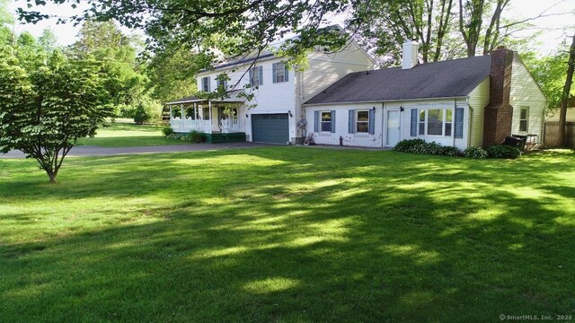 77 Bassett Rd, North Haven, CT 06473 - view of front of house with a garage, driveway, a chimney, and a front lawn