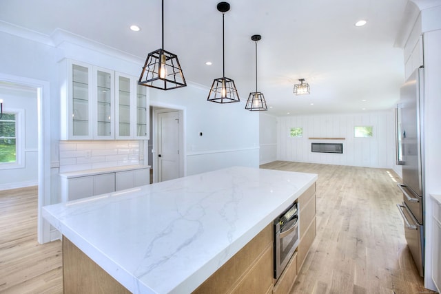 59 Thornhill Rd, Fairfield, CT 06824 - kitchen featuring healthy amount of natural light, high end fridge, light wood-type flooring, glass insert cabinets, and crown molding