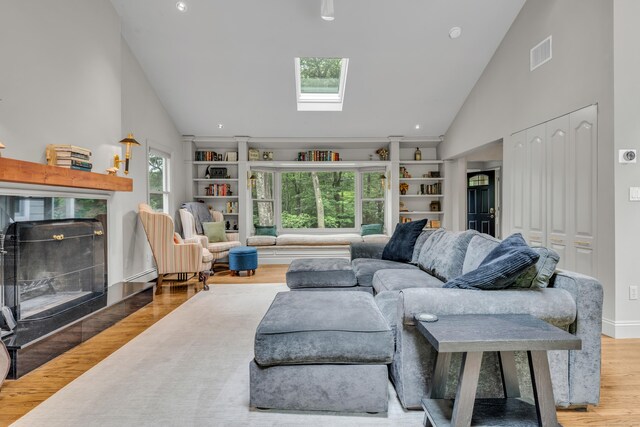 15 Hallsey Ln, Woodbridge, CT 06525 - living room featuring high vaulted ceiling, a skylight, wood finished floors, built in shelves, and a fireplace
