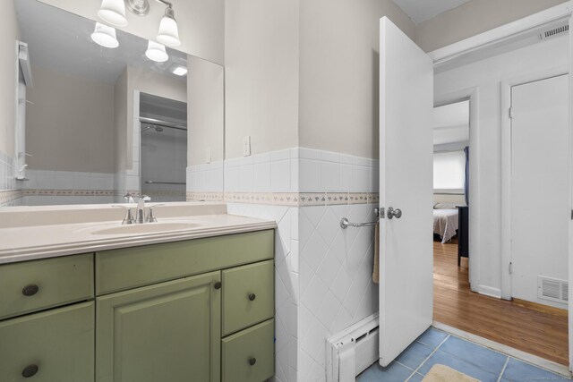 7 Lorma Ave, Trumbull, CT 06611 - ensuite bathroom with a baseboard radiator, tile patterned flooring, vanity, a wainscoted wall, and tile walls