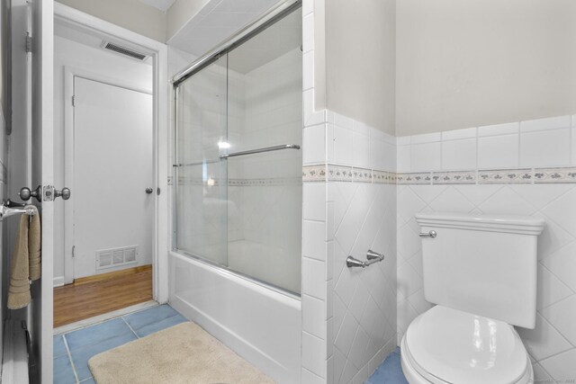 7 Lorma Ave, Trumbull, CT 06611 - full bathroom with toilet, shower / bath combination with glass door, tile patterned flooring, tile walls, and wainscoting